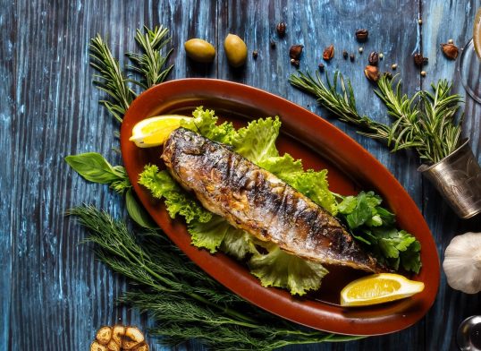 Baked mackerel with lemon on a rustic wooden background