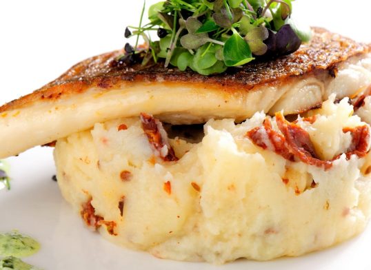 Tasty healthy fish fillet with potato puree with dried tomatoes and wild garlic sauce