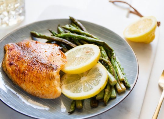 Baked tilapia fish with asparagus on a ceramic plate. Healthy mediterranean diet lunch or dinner.
