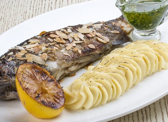 Baked trout with almonds and mashed potatoes. On white background