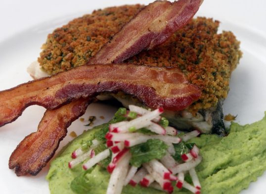 Pan fried barramundi fillet with herb crust, served with wild garlic potato mash and crispy bacon on top
