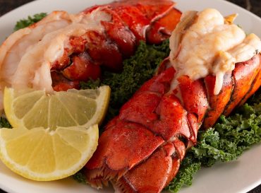 Two Broiled Lobster Tails on a Bed of Kale with Lemon Slices