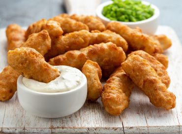 Battered Haddock fish, mini fingers with mashed peas, tartar sauce on white wooden board