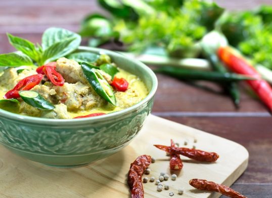 Green curry with fish ball in green chalice on wooden table