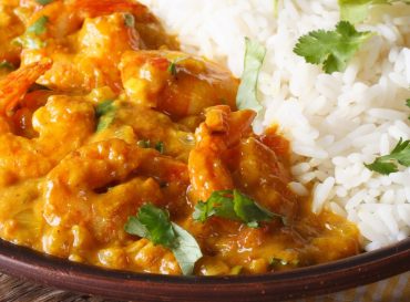 Shrimps in curry sauce with rice and cilantro horizontal