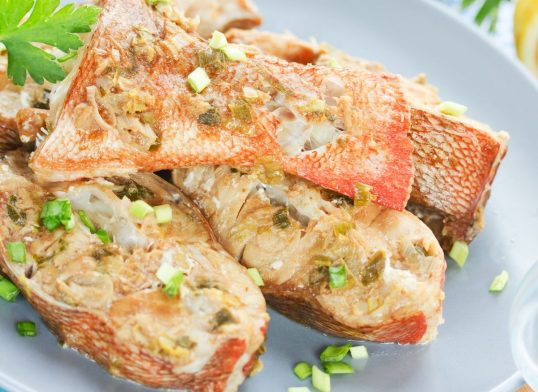 Steamed snapper (pacific ocean perch, sea bass, ruby perch) with soy sauce, lemon, ginger and parsley in Asian style