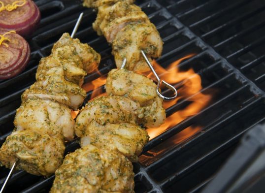 Marinated monkfish kebabs and onions on a barbecue