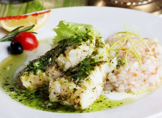 white fish with pesto sauce and meat plate in a still life gourmet restaurant