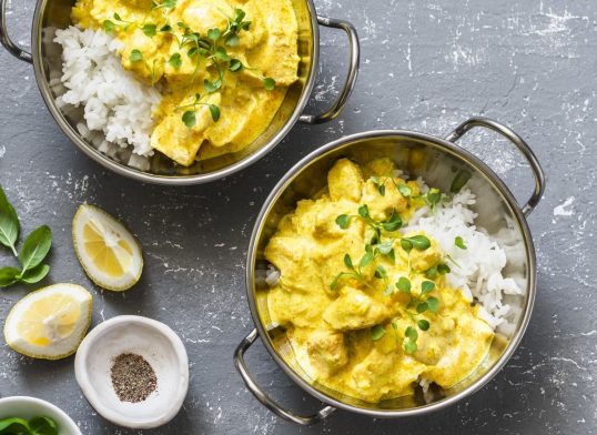 Salmon curry and rice in curry dishes on grey background, top view. Indian cusine style. Flat lay