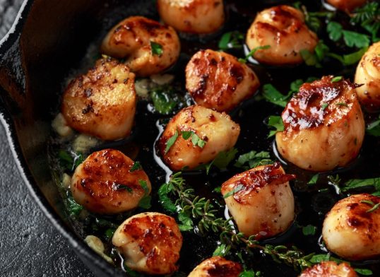 Scallops seared in garlic and parsley butter served in cast iron skillet